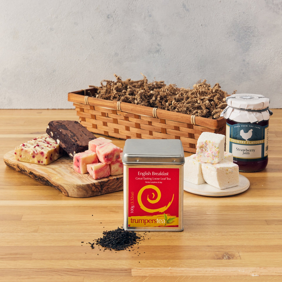 Tea time setting with jam, tea, and scones on a wooden board.