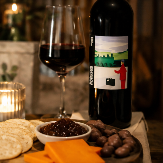 Cosy red wine hamper with cheese, crackers, crisps and artisan treats by the fire