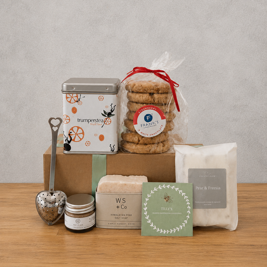Collection of products including cookies, tea, and a candle on a wooden surface with a gray background.