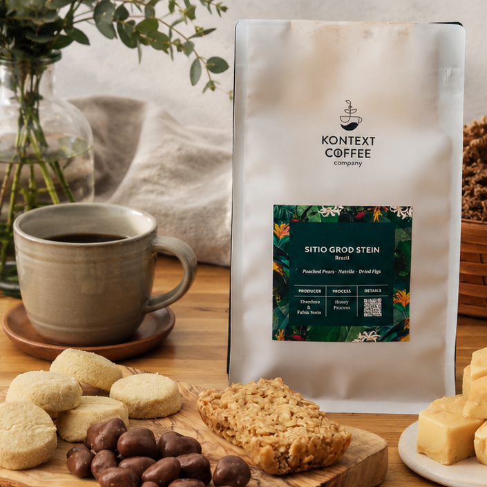 Kontext Coffee bag with a cup of coffee, cookies, and coffee beans on a wooden table.