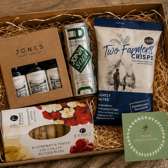 Gift box with Apple Soda, Two Farmers Crisps, and other snacks on a wooden surface.